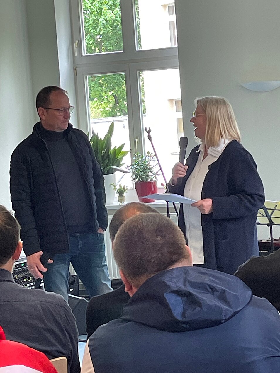 Frau spricht mit Mikrofon vor Publikum