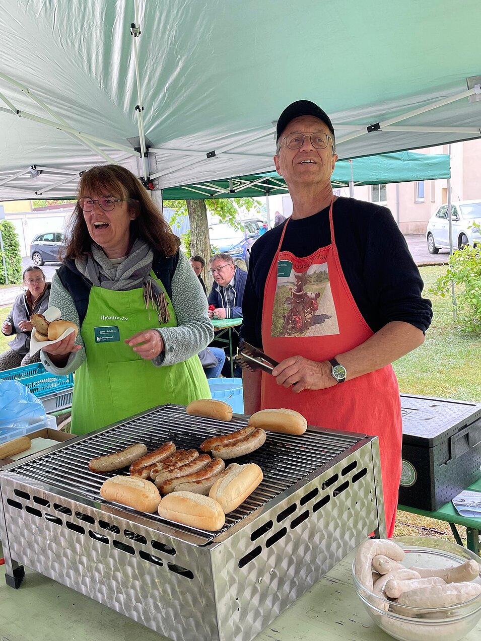 Zwei Personen grillen Würstchen im Zelt