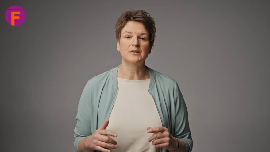 Frau spricht vor grauem Hintergrund, oben links ein pink-oranges F-Logo.